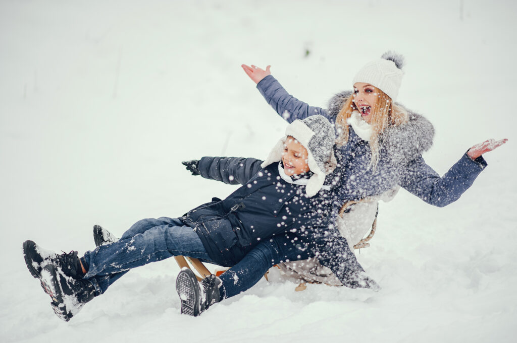 Women and child having fun sledding in the snow